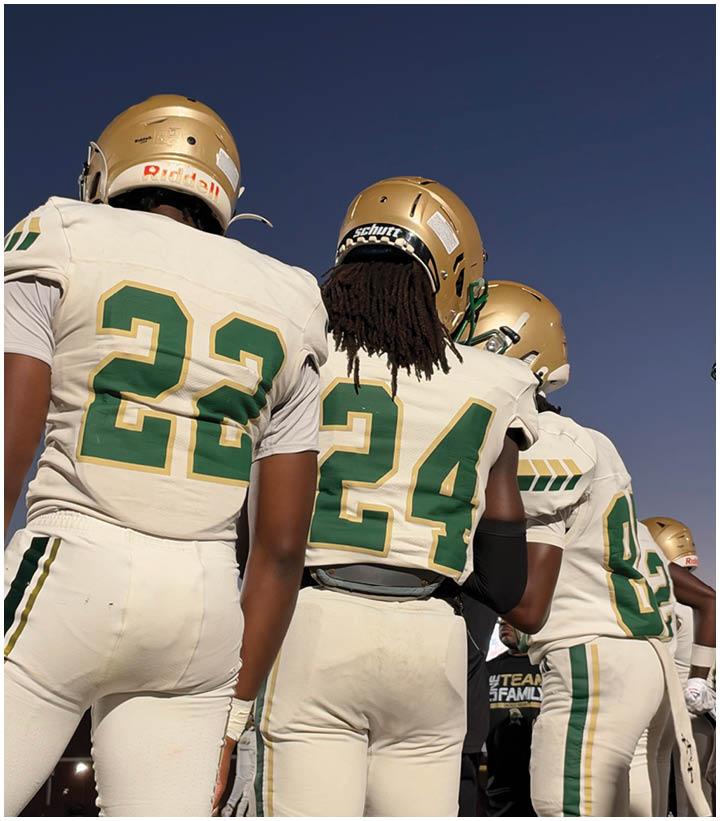 Three people wearing football uniforms with gold helmets and white jerseys numbered 22, 24, and 83 stand together under a clear blue sky. Description generated by AI