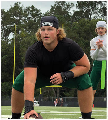 Two people wearing sports headbands and athletic clothing are outdoors with trees in the background, one person is leaning forward while the other claps hands. Description generated by AI