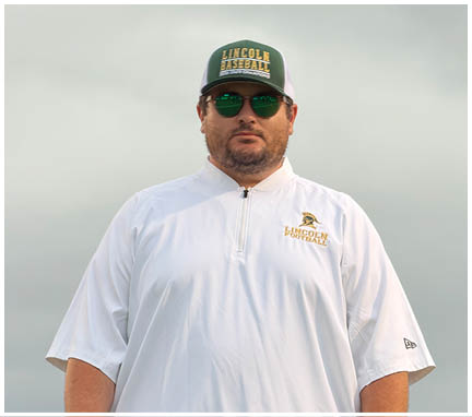 A person wearing sunglasses, a white Lincoln Baseball shirt, and a matching cap stands outdoors under a cloudy sky. Description generated by AI