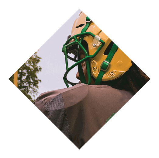 A close-up of a yellow football helmet with a green faceguard and strap against a plain light background. Description generated by AI