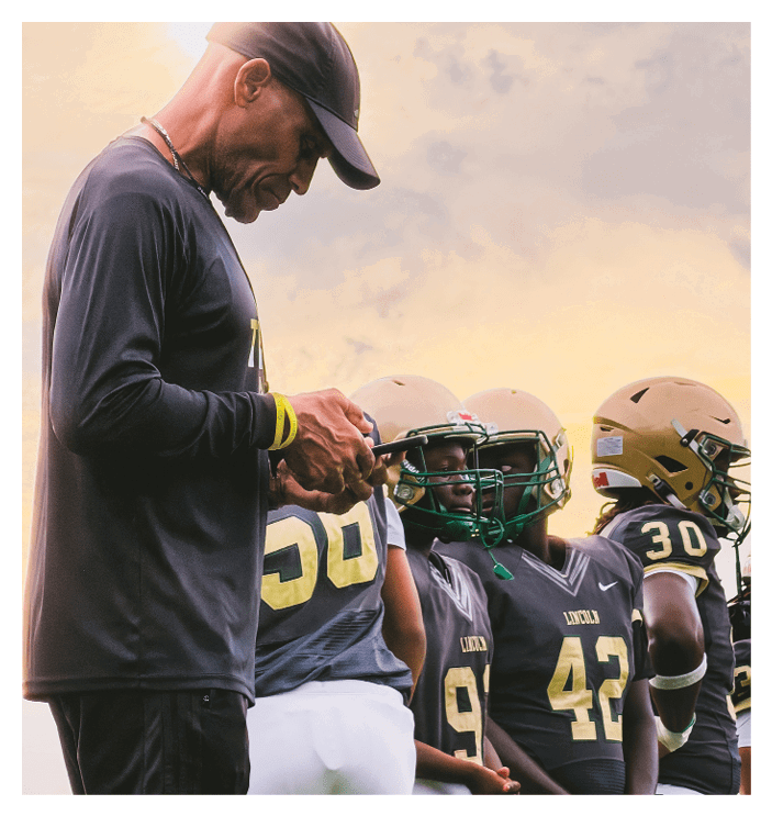A group of people wearing football helmets and uniforms stand closely together, appearing focused and ready for a game. Description generated by AI