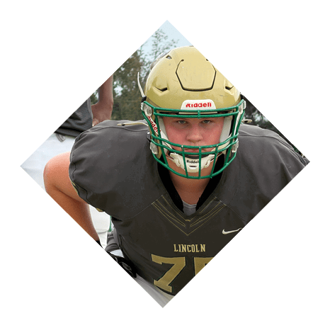 A person wearing a football helmet and uniform with the number 75 is crouched in a ready position on a football field. Description generated by AI