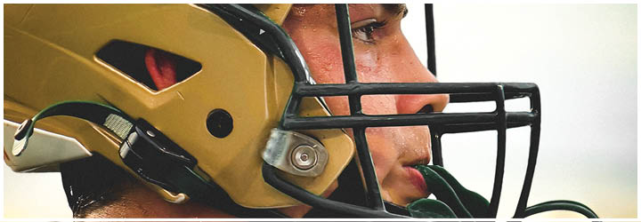 A person wearing a gold football helmet with a black faceguard is shown in close-up profile view. Description generated by AI
