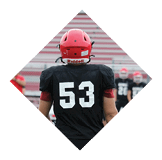 A person wearing a black football uniform with the number 53 on the back is standing on a football field with other players in the background. Description generated by AI