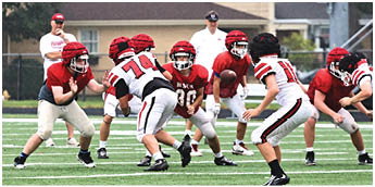 A person wearing cleats is running on a green artificial turf field marked with white lines. Description generated by AI