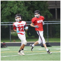 Two people wearing football helmets and uniforms are running on a sports field during a game or practice. Description generated by AI