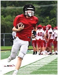 A group of people wearing red helmets and white jerseys with red pants are standing together on a sports field. Description generated by AI