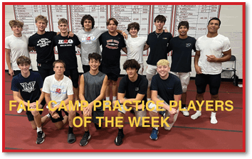 A group of people wearing casual athletic clothing pose together indoors on a red floor with a white wall and large boards displaying names and numbers behind them, with text overlay reading “FALL CAMP PRACTICE PLAYERS OF THE WEEK." Description generated by AI