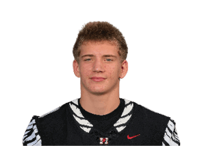 A person wearing a black football jersey with the number nine and the word “HAWKS" stands with hands behind their back against a black background. Description generated by AI