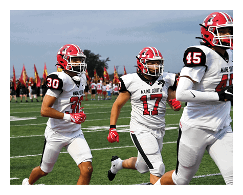 Three people in white football uniforms with red helmets and gloves are running on a green field during a game. Description generated by AI