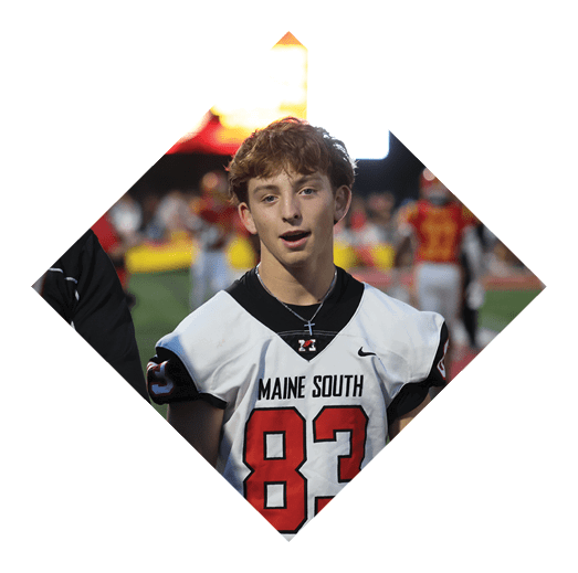 A person wearing a white Maine South football jersey with the number 83 stands on a sports field with another person partially visible nearby. Description generated by AI