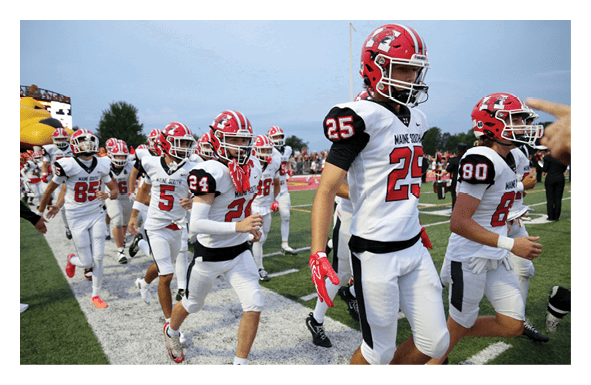 People wearing white sports uniforms with red and black details are running on a football field. Description generated by AI
