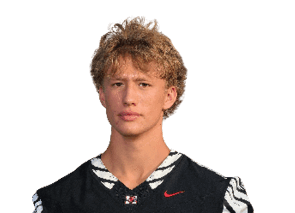 A person with curly hair wearing a black sports jersey with white and black patterned sleeves and a red Nike logo is looking directly at the camera. Description generated by AI