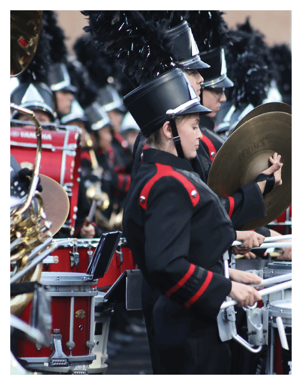 People in black and red marching band uniforms are playing percussion instruments in a formation. Description generated by AI
