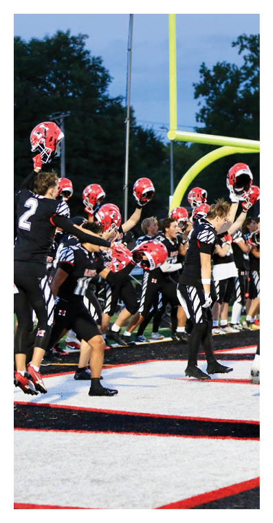 People in football uniforms celebrating on a field near a goalpost during a game. Description generated by AI
