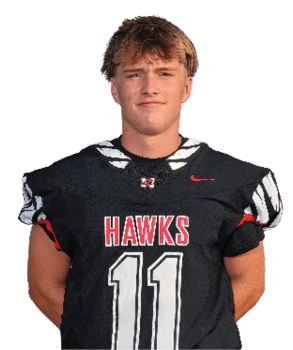A person with short hair wearing a black sports jersey with the word “HAWKS" and the number 11 on the front is looking forward with a neutral expression. Description generated by AI