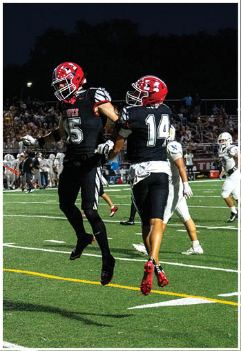 A person wearing a black football uniform with the number zero is kicking a football on a field at night. Description generated by AI