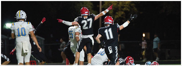 Two teams of football players are on the field with some players celebrating while others are on the ground near the end zone and a referee watches nearby. Description generated by AI