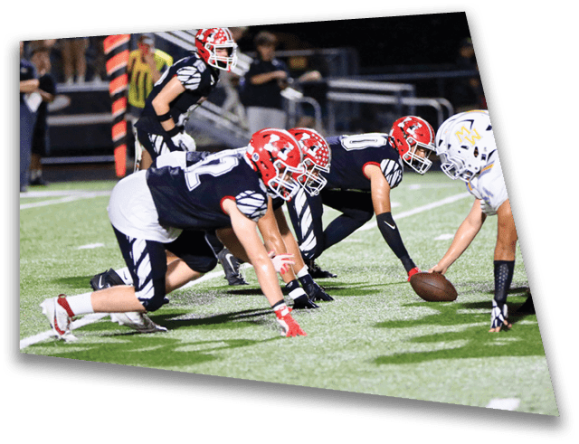 Two opposing American football teams are lined up at the line of scrimmage on a field, ready for the play to begin. Description generated by AI