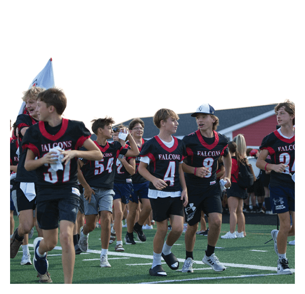 A group of young people wearing Falcons sports jerseys are walking and talking together on a field with a building in the background. Description generated by AI