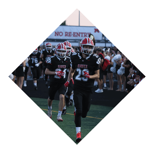 A person wearing a black sports uniform with the number 73 is running on a field near cheerleaders standing on the sidelines next to an orange marker with the letter G. Description generated by AI