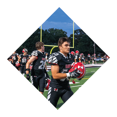 People wearing black football uniforms with white and red accents are standing on a field near a yellow goalpost during a game. Description generated by AI