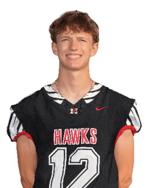 A person with short curly hair is wearing a black sports jersey with the word “HAWKS" and the number 12 while smiling. Description generated by AI