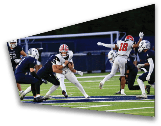 A group of people in football uniforms are actively playing on a field with one person holding the ball while others are running and preparing to tackle. Description generated by AI