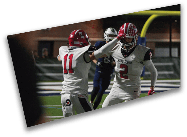Two people in football uniforms are celebrating on a field during a game. Description generated by AI
