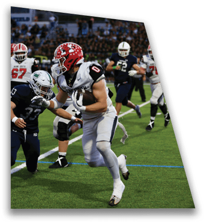 A group of people wearing football uniforms are actively playing on a green field with a crowd in the background. Description generated by AI
