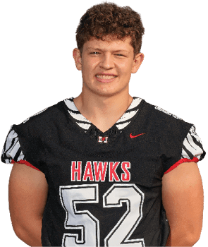 A person wearing a black sports jersey with the word “HAWKS" and the number 52 is smiling. Description generated by AI