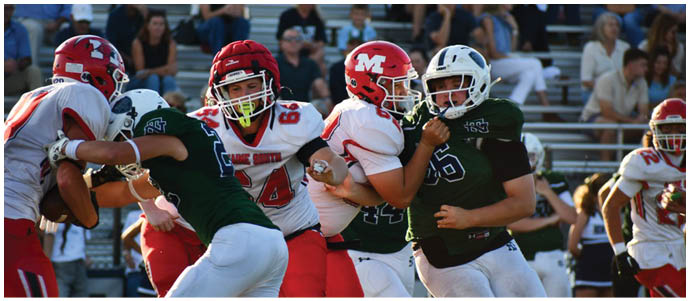 People wearing sports uniforms are engaged in a football game, with some players in red pants and others in white pants and dark jerseys. Description generated by AI