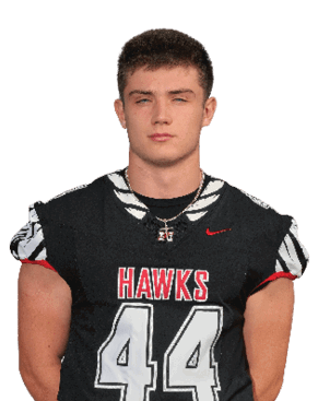 A person with short hair wearing a black sports jersey with the number 44 and the word “HAWKS" stands facing forward against a white background. Description generated by AI