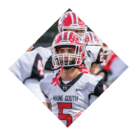 Two people wearing red and white football helmets with star patterns are standing close together outdoors. Description generated by AI
