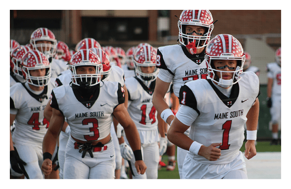 A group of people in white football uniforms with red and black helmets are running onto a field, led by a person wearing number 1. Description generated by AI