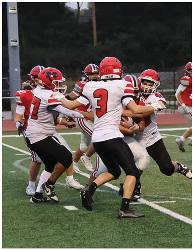 Two people in red football uniforms and helmets are on a football field preparing for a play during a game. Description generated by AI