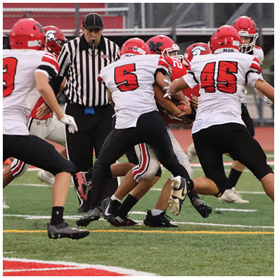 Several people in football uniforms are actively engaged in a play on a green field with white and yellow lines. Description generated by AI