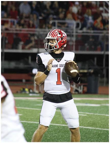A person wearing a red and white football helmet and a white uniform with the number one is preparing to throw a football on a field while another player in a similar uniform with the number twenty-two is in the foreground. Description generated by AI
