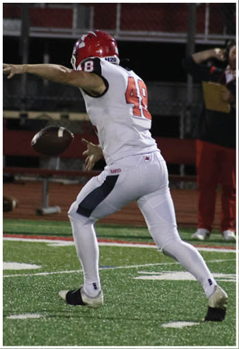 A person wearing a white sports uniform with the number 48 is catching or throwing a football on a green field with white yard lines. Description generated by AI