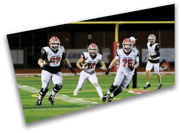 Several people in football uniforms are running on a field during a game, with one person holding the ball. Description generated by AI