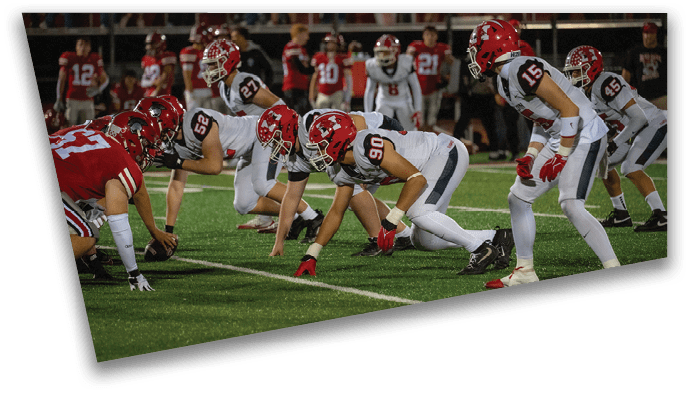 Two opposing American football teams are lined up facing each other on the field, ready for the next play. Description generated by AI