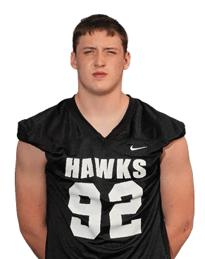 Person with short hair wearing a black sports jersey with the word “HAWKS" and a Nike logo on the front. Description generated by AI