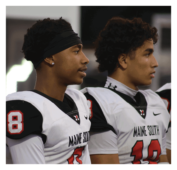 Two people wearing white and black sports jerseys with numbers and the text “MAINE SOUTH" are standing side by side, looking to the right. Description generated by AI