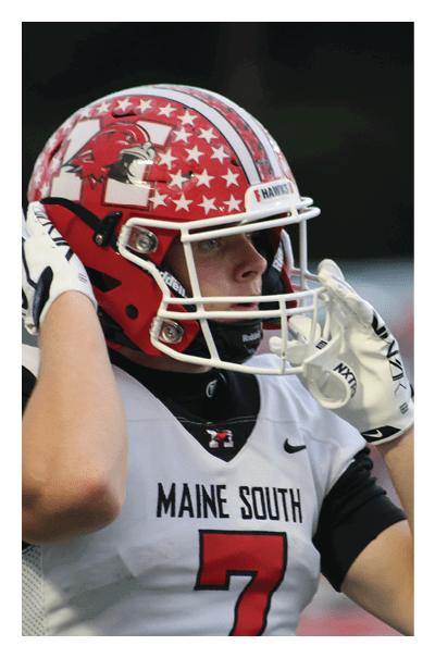 A person wearing a red football helmet and white jersey with “MAINE SOUTH" and the number 7 is adjusting their white glove near their face. Description generated by AI