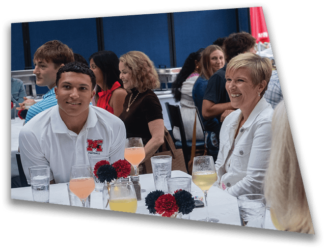 Several adults are seated around a table with drinks, engaged in conversation and smiling in a casual social setting. Description generated by AI