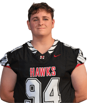 A person with short curly hair is wearing a black sports jersey with the word “HAWKS" and the number 24 on it, smiling slightly against a white background. Description generated by AI
