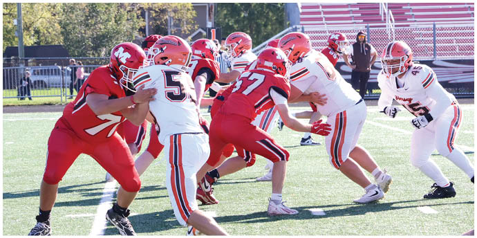 Adults in football uniforms are engaged in a blocking drill on a green field during daylight. Description generated by AI