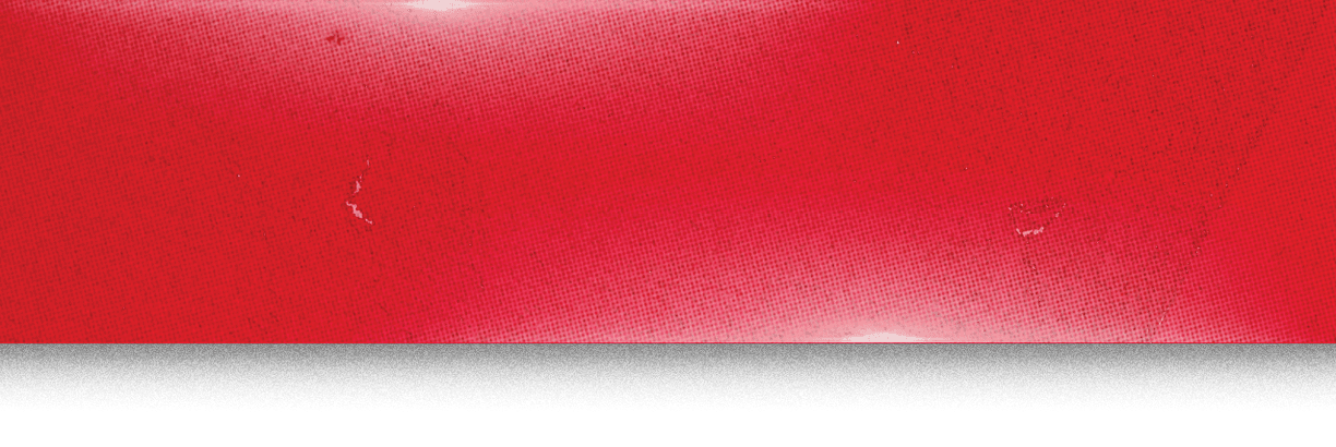 A close-up of a red surface with subtle texture and a few small imperfections. Description generated by AI