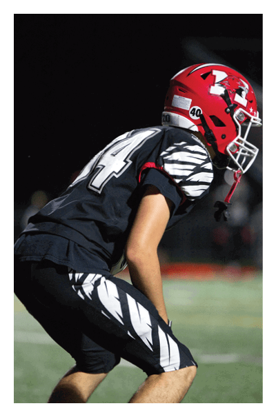 A person wearing a black sports jersey with the number 14 is partially visible against a dark background. Description generated by AI