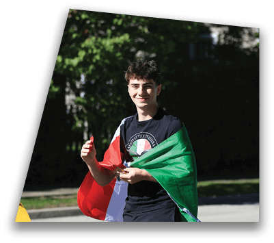 A person smiling and walking outdoors while wrapped in a flag with red, white, and green colors. Description generated by AI